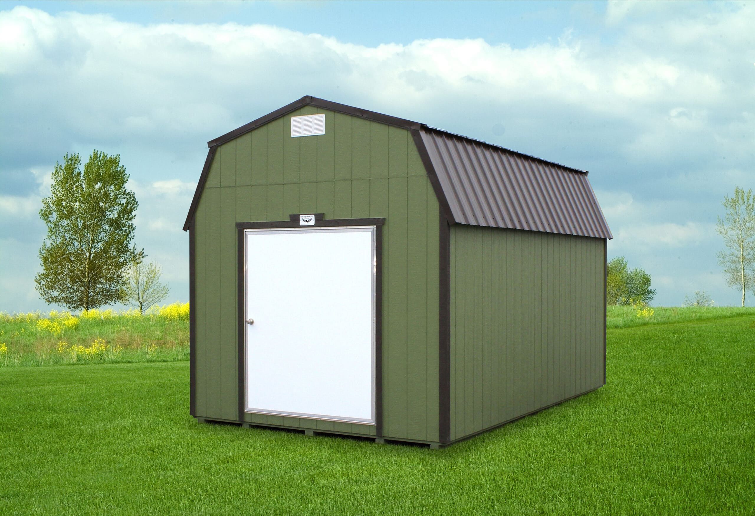 An 8x16 high barn shed with a traditional gambrel roof and a green-painted exterior, accented by dark brown trim and a white door. The shed features a sturdy metal roof, providing durability and a classic aesthetic. A small vent is positioned at the peak for airflow, ensuring proper ventilation. The shed is set on a lush, grassy field surrounded by an open landscape of trees and wildflowers under a partly cloudy sky, blending seamlessly with the natural environment.
