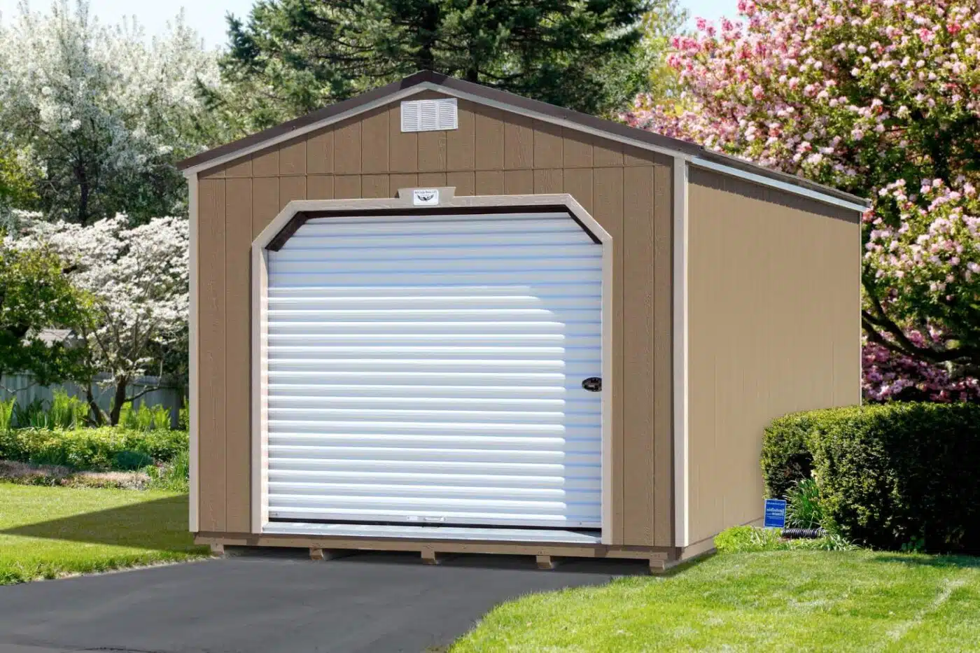 Brown shed with white garage door set on wooden foundation on concrete