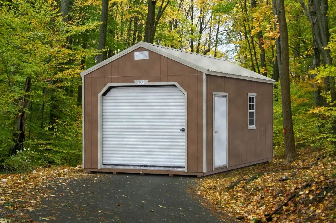 Beige shed in forest with white door, trim, and roof. Set on concrete paver