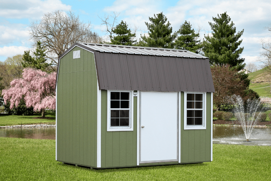 green side lofted barn shed with white trim curved brown metal roof and two windows on either side of white front door